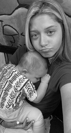 a black and white photo of a woman holding a baby in front of her face