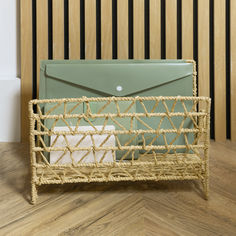 a wicker mail holder with an envelope in it on a wooden floor next to a striped wall