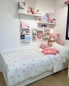 there is a teddy bear sitting on top of the bed in this small child's room