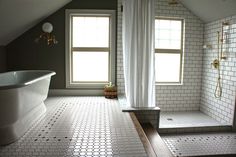 a large bathroom with white tile floors and two windows in the ceiling, along with a claw - foot tub