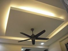 a ceiling fan in a room with white walls and lights on the ceiling above it