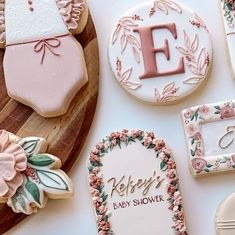 some decorated cookies are sitting on a wooden platter with the letters e, f, and baby's name