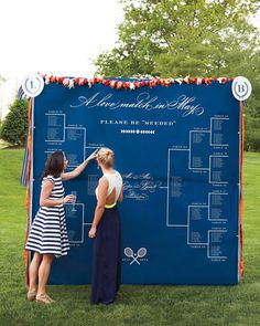 two women standing in front of a large blue board with a family tree on it