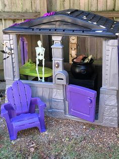 there is a purple toy house with two chairs and a table in the back yard