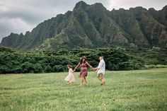 three people holding hands while walking through the grass