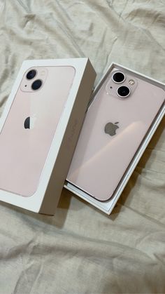 two new iphones in their boxes on a bed