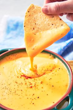 a person dipping cheese into a bowl of dip