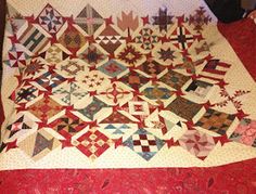 an old quilt is laying on the floor next to a red tablecloth and chair