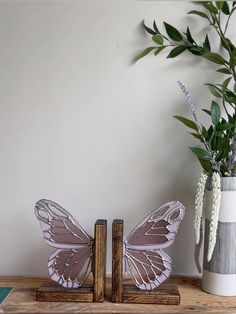 two butterflies are sitting next to each other on a shelf with flowers in vases