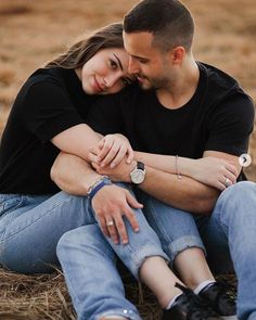 a man and woman sitting on the ground hugging each other with their arms around each other