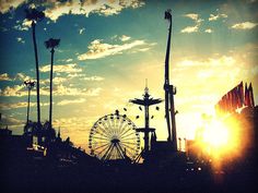 the sun is setting over an amusement park