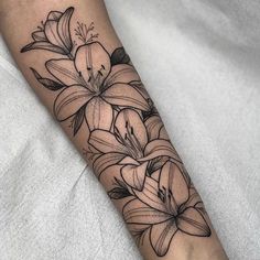 a black and white flower tattoo on the left arm, with flowers in blooming