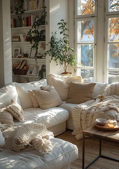 a living room filled with lots of white furniture and pillows on top of a couch