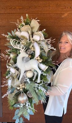 a woman standing next to a christmas wreath with deer and snowflakes on it