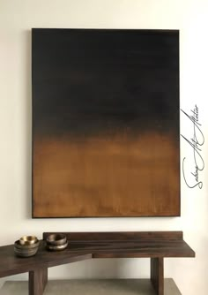 an abstract painting hangs on the wall above a wooden bench with two bowls below it