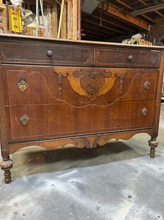 an old wooden dresser with ornate carvings on the front and sides, sitting in a warehouse