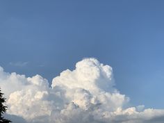 a large cloud is in the sky above some trees