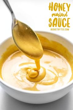 honey mustard sauce being poured into a white bowl with a spoon in it and the words honey mustard sauce on top