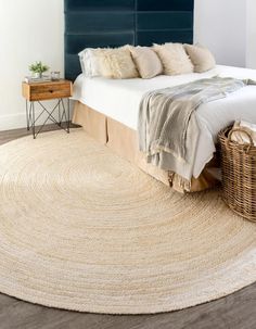 a large round rug on the floor in front of a bed with blue headboard