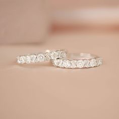 two white gold wedding rings with diamonds on top of each other and one diamond in the middle