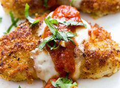 chicken parmesan with tomato sauce and fresh herbs on the side, ready to be eaten