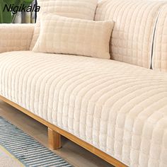 a white couch sitting on top of a hard wood floor next to a potted plant