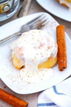 a plate topped with an egg covered in icing next to cinnamon sticks and a fork