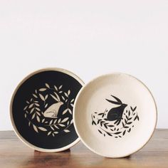 two black and white plates sitting on top of a wooden table next to each other