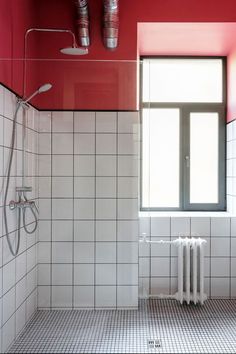 a bathroom with red walls and white tile flooring next to a radiator