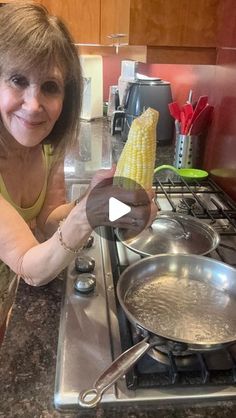 a woman is smiling while cooking corn on the cob