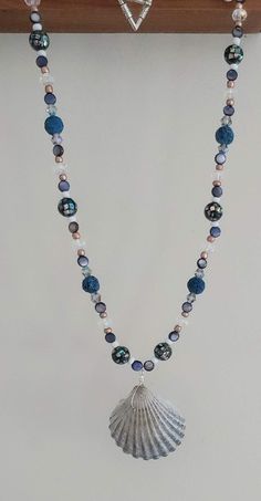 This necklace is made with navy lava beads, natural shell beads, gold seed beads, clear rondelles, multi-color bicone crystal beads, speckled beads, and a scallop shell in the middle. Toggle clasp. Measures 21 inches long end to end. Seashell Jewelry, Scallop Shell, Ocean Jewelry, Lava Beads, Scallop Shells, Seashell Crafts, Lava Bead, Shell Necklace, Shell Crafts