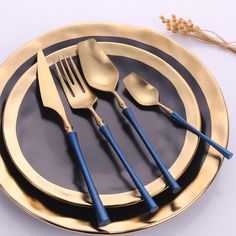 there are five forks and two spoons on the plate with gold rimmed plates