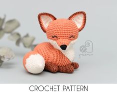 a crocheted stuffed fox sitting next to some white flowers and greenery with the words crochet pattern written below it