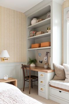 a bedroom with a bed, desk and shelves in the corner next to a window