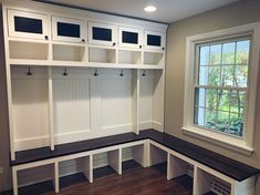 a mud room with white cabinets and benches