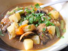 a bowl filled with stew and vegetables on top of a table