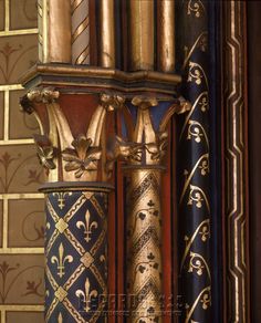 an ornate gold and blue column in front of a brick wall with decorative designs on it