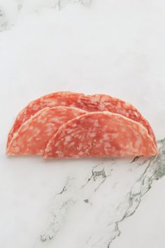 three slices of salami on a marble surface