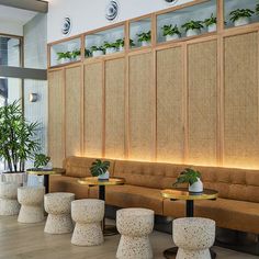 an indoor seating area with plants on the wall and stools in front of it