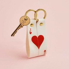 two keys are attached to a pair of white leather keychains with red hearts on them