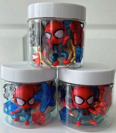 three plastic containers filled with different types of spider - man figurines and toys