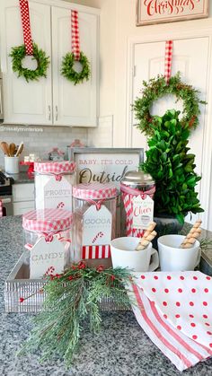 the kitchen counter is decorated for christmas with red and white napkins, cups, and wreaths