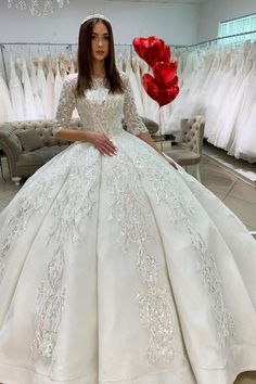 a woman in a white wedding dress is standing next to some dresses on hangers