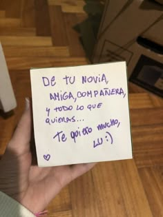 a hand holding a piece of paper that has writing on it in spanish and english