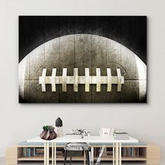 an abstract painting of a football on a wall above a table with books and vases