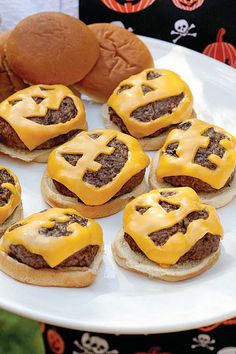 some hamburgers with cheese on them are sitting on a plate next to a stuffed animal