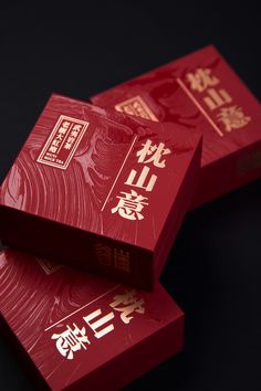 two red boxes with chinese writing are stacked on top of each other in front of a black background