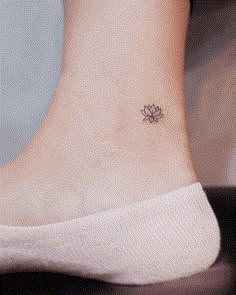 a small tattoo on the ankle of a woman's foot with a lotus flower