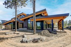 a large house with lots of windows in the middle of trees and dirt on the ground