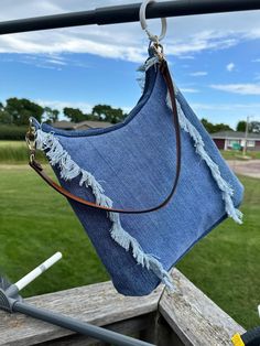 a blue bag hanging from a wooden rail in front of a green grass covered field